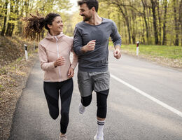 A man and a woman run down a road.