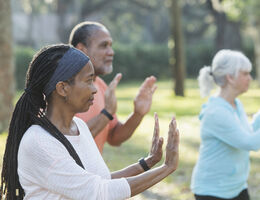 A woman does tai chi in an outdoor class.