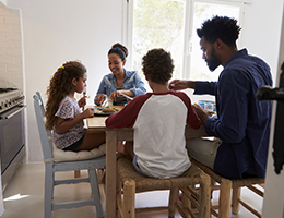A family of four shares a meal at their kitchen table.