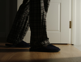 A pair of pajama- and slipper-clad legs enter a bathroom at night.