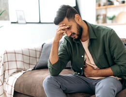 A man grimaces and holds his stomach.