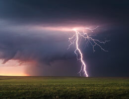 Lightning striking an open field.