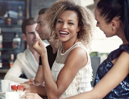 Two women laughing at a coffee bar.