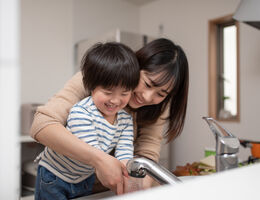  A mom helping a boy wash his hands.