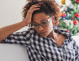 A woman sits on a couch, thinking.