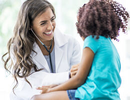 A doctor smiles as she examines a child