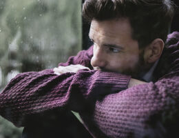 A man looks out a window at the rain