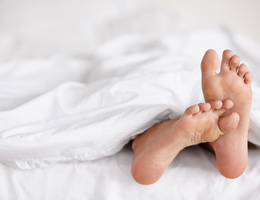  Bare feet sticking out from beneath white covers. 
