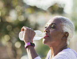 An older woman drinks bottled water.