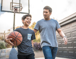 A parent and a child play basketball. 