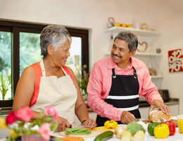 A couple smile as they cook together.