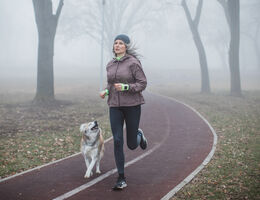 A woman jogs with a dog.