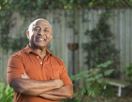 A smiling man stands with his arms crossed.