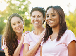 Three smiling women in pink shirts.