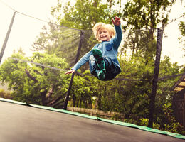A boy bouncing on a backyard trampoline.
