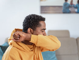 A man coughs into his elbow.