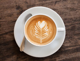 Milk in a latte forming a leaf shape with a heart on top.