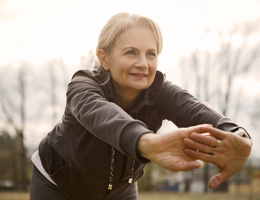 An older woman leans forward as she stretches
