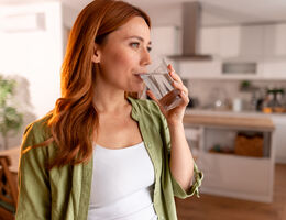 A woman drinks a glass of water.