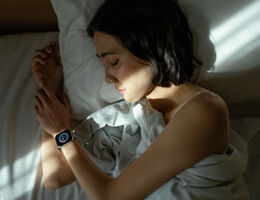 A woman sleeping with a sleep tracker on her wrist.