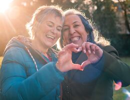 Two women form a heart with their combined hands.