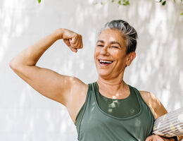 An older woman flexes her biceps.