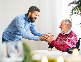 A man hands a mug to older man.