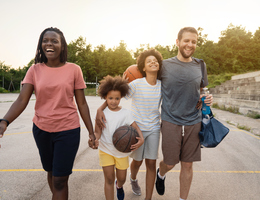 A family walks together while carrying basketball gear
