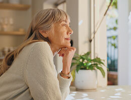 A smiling woman looks out her window.