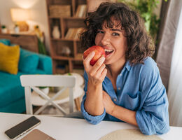 A woman bites into an apple.