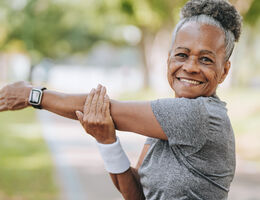 A smiling woman in workout clothes stretches.