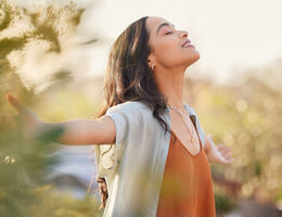 A woman stands with arms outstretched.