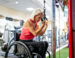 A woman in a wheelchair uses gym equipment.