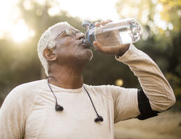 A man in workout clothes drinks from a water bottle.