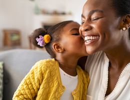 A little girl kisses a woman on the cheek.