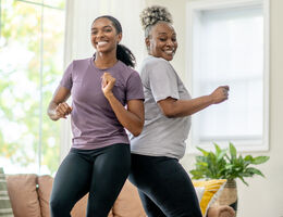 Two women dance in a living room.