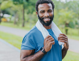 A man stands outside with a workout towel draped around his neck.