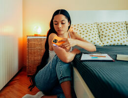 A woman holds a phone to her glucose monitor.