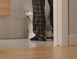 A man's pajama-clad legs seen through a bathroom door.