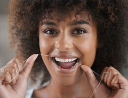 A woman flosses her teeth.