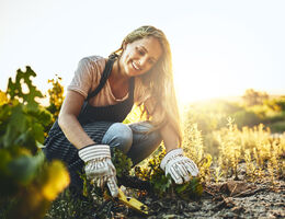 A woman digs with a garden trowel.