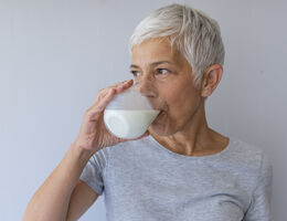 A woman drinks a glass of milk.