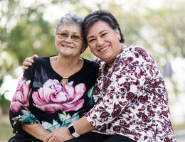  A smiling woman with her arm around a smiling older woman.