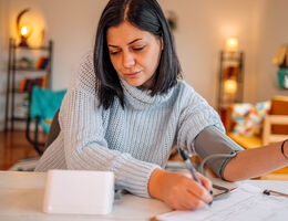 A woman checks her blood pressure at home.